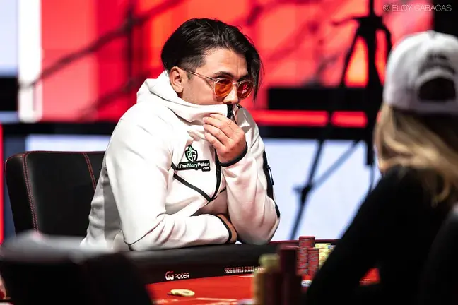 Giuseppe Calio en una mesa de torneo en vivo, con buzo blanco y lentes de sol de cristal naranja.